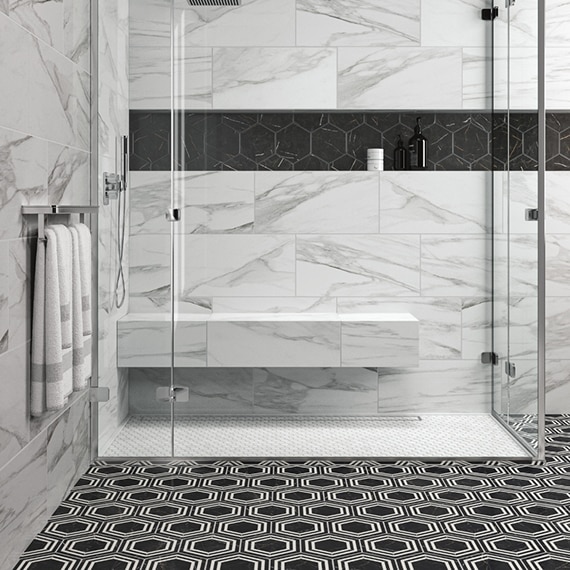 Shower with white penny round shower floor tile, white & gray wall tile that looks like marble, niche with black hexagon tile, and black & white hexagon bathroom floor tile.